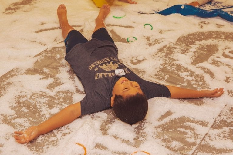 Holiday Hoopla Camper making a snow angel on the floor